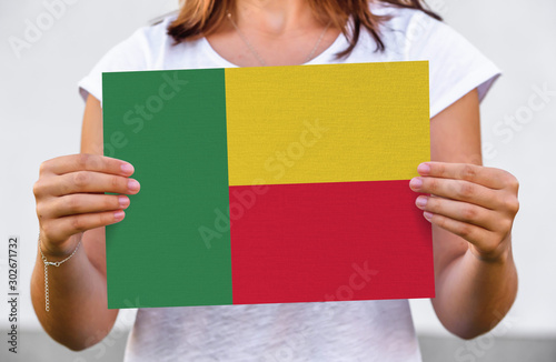 woman holds flag of Benin on paper sheet