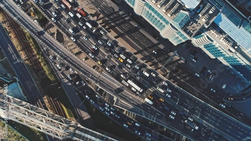 Aerial drone top zoom of freeway busy traffic jam highway in industrial area. Drone shot of cars in peak hour in summer at daylight