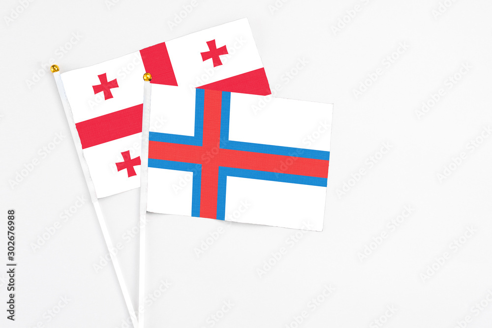 Faroe Islands and Georgia stick flags on white background. High quality fabric, miniature national flag. Peaceful global concept.White floor for copy space.