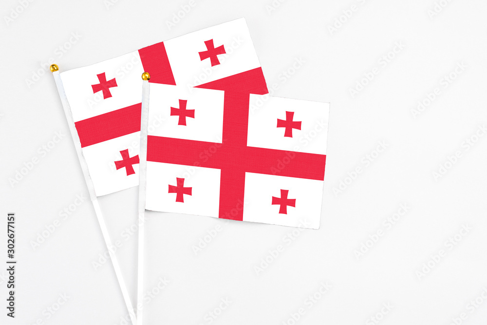 Georgia and Georgia stick flags on white background. High quality fabric, miniature national flag. Peaceful global concept.White floor for copy space.