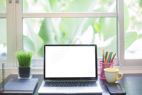Computer laptop with white blank screen isolated  on work table in office.
