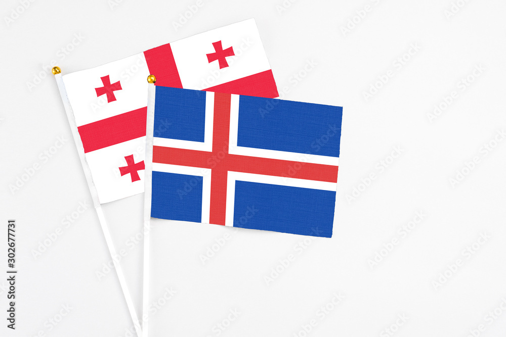 Iceland and Georgia stick flags on white background. High quality fabric, miniature national flag. Peaceful global concept.White floor for copy space.