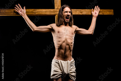 Bild auf Leinwand shirtless man crucified on wooden cross screaming isolated on black