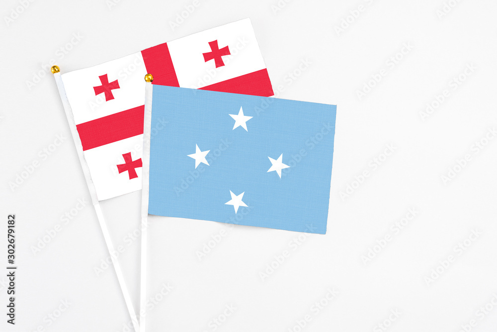 Micronesia and Georgia stick flags on white background. High quality fabric, miniature national flag. Peaceful global concept.White floor for copy space.