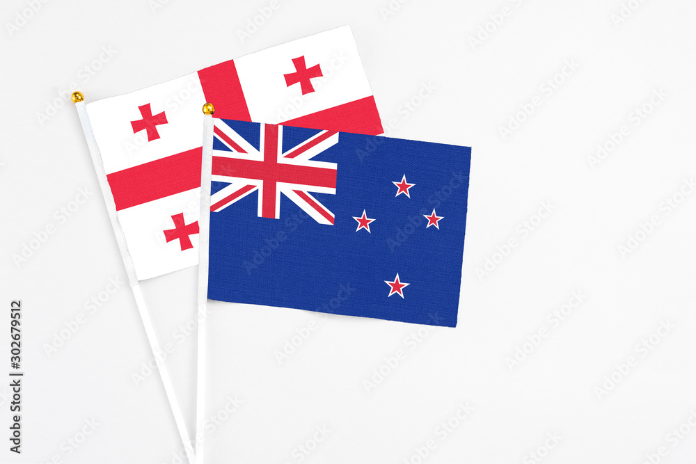 Fototapeta premium New Zealand and Georgia stick flags on white background. High quality fabric, miniature national flag. Peaceful global concept.White floor for copy space.