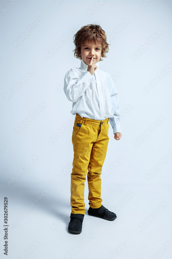 Pretty young boy in casual clothes on white studio background. Fashionable posing. Caucasian male preschooler with bright facial emotions. Childhood, expression, having fun. Whispering secrets. Pretty young boy in casual clothes on white studio background. Fashionable posing. Caucasian male preschooler with bright facial emotions. Childhood, expression, having fun. Whispering secrets.