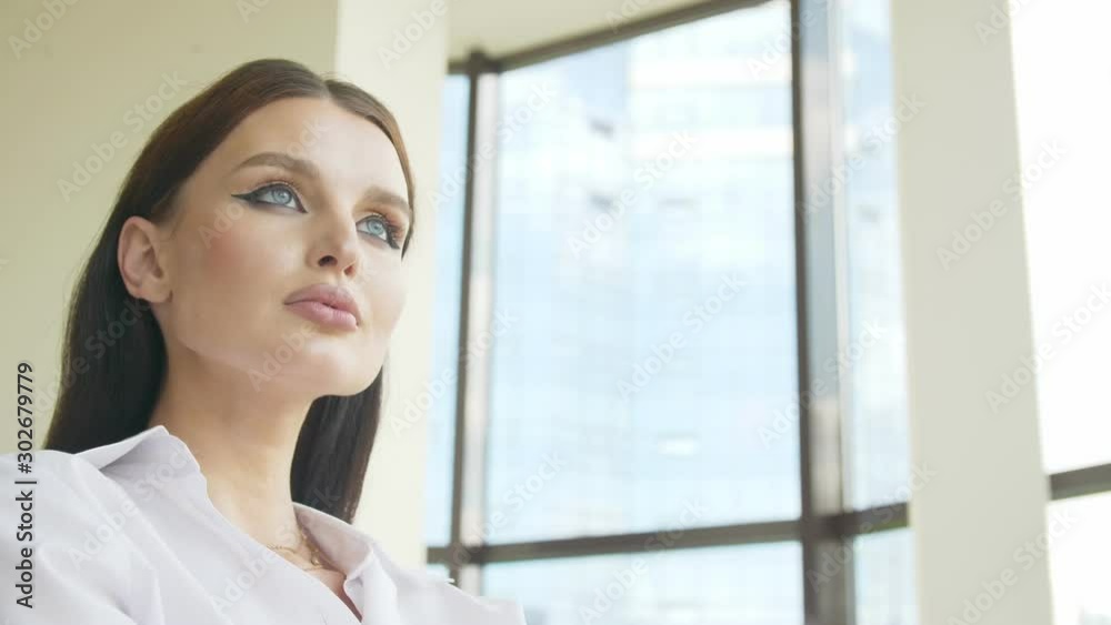 Justification of hopes Confident look into the future Look of a young beautiful woman in a business suit She looks at the light from the window Justification of hopes Confident look into the future Look of a young beautiful woman in a business suit She looks at the light from the window