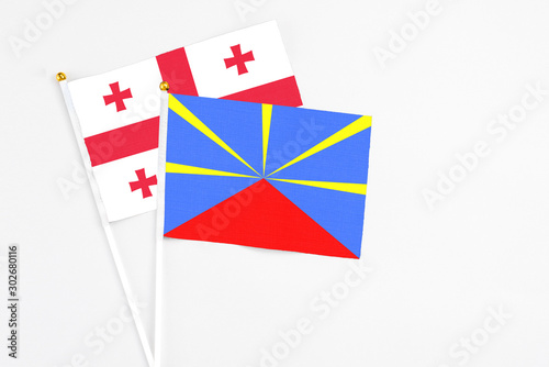 Reunion and Georgia stick flags on white background. High quality fabric, miniature national flag. Peaceful global concept.White floor for copy space.