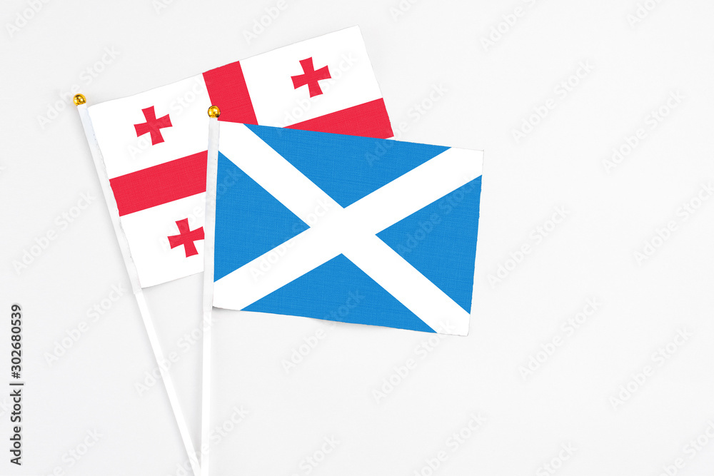 Scotland and Georgia stick flags on white background. High quality fabric, miniature national flag. Peaceful global concept.White floor for copy space.