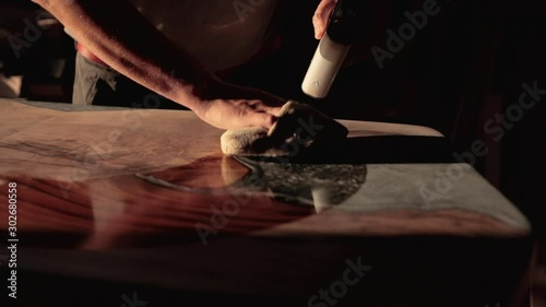 Carpenter pouring oil on wooden table and polishing