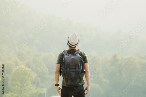 Hiker with backpack standing on street and enjoying mountain.Concept of success