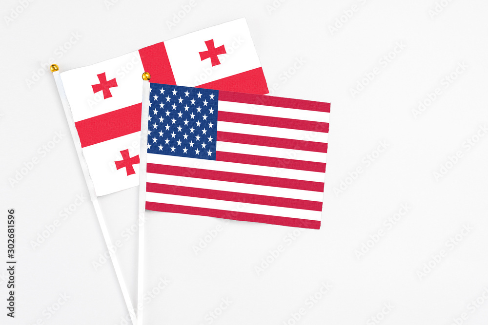 United States and Georgia stick flags on white background. High quality fabric, miniature national flag. Peaceful global concept.White floor for copy space.