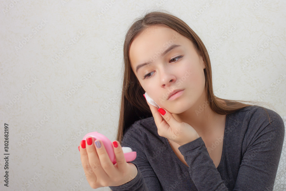 Health and beauty. Facial skin care. A young girl rubs her face with a tonic, nourishing lotion. Health and beauty. Facial skin care. A young girl rubs her face with a tonic, nourishing lotion.
