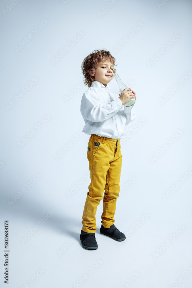 Pretty young boy in casual clothes on white studio background. Fashionable posing. Caucasian male preschooler with bright facial emotions. Childhood, expression, having fun. Drinking milk, smiling, Pretty young boy in casual clothes on white studio background. Fashionable posing. Caucasian male preschooler with bright facial emotions. Childhood, expression, having fun. Drinking milk, smiling,