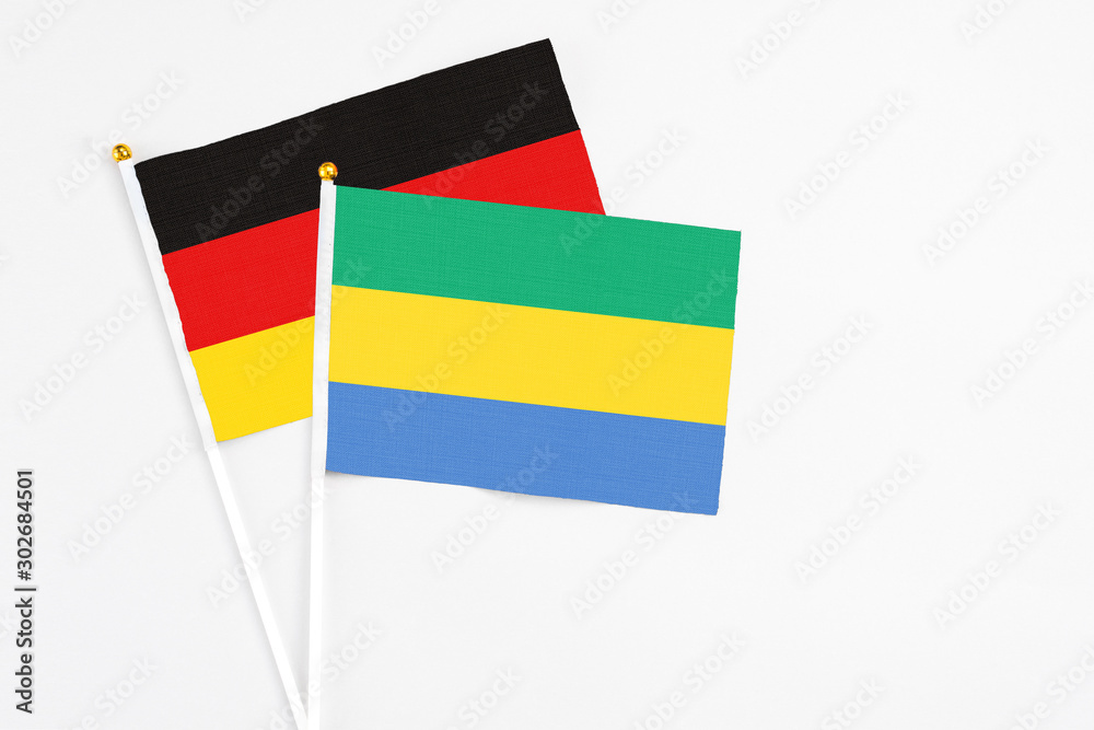 Gabon and Germany stick flags on white background. High quality fabric, miniature national flag. Peaceful global concept.White floor for copy space.