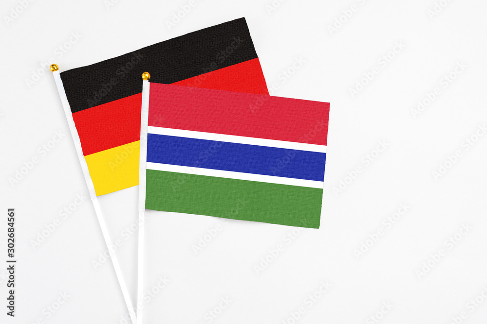 Gambia and Germany stick flags on white background. High quality fabric, miniature national flag. Peaceful global concept.White floor for copy space. Gambia and Germany stick flags on white background. High quality fabric, miniature national flag. Peaceful global concept.White floor for copy space.