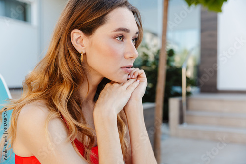 Photo of nice woman looking forward while sitting on chaise lounge