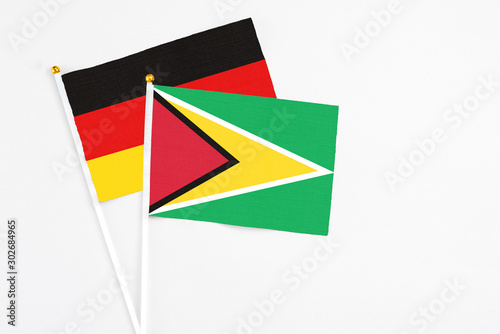 Free Download Guyana and Germany stick flags on white background. High quality fabric, miniature national flag. Peaceful global concept.White floor for copy space. - GFXLoad