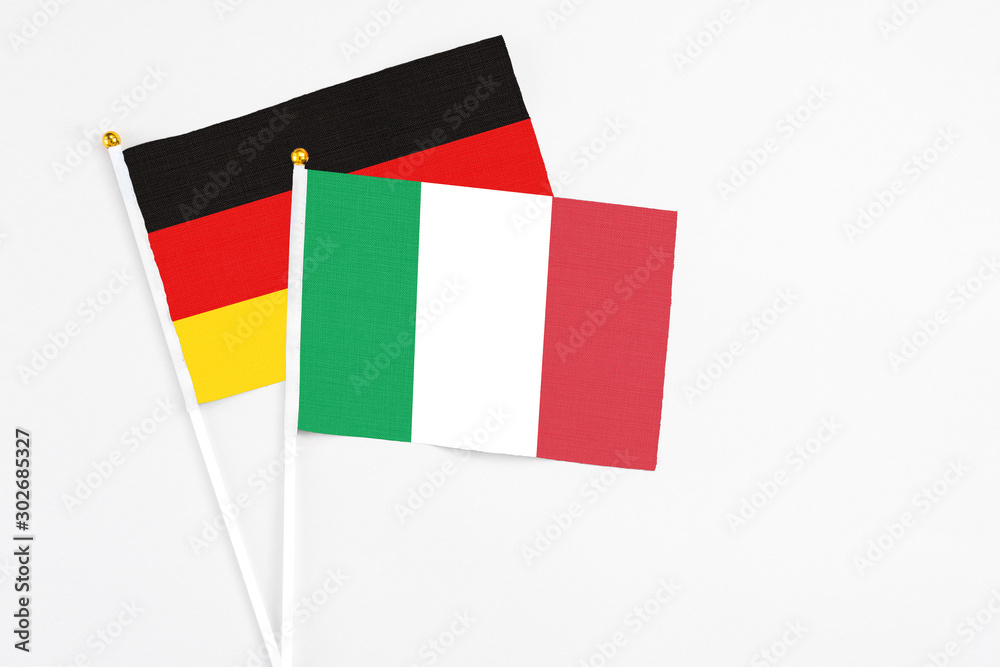 Italy and Germany stick flags on white background. High quality fabric, miniature national flag. Peaceful global concept.White floor for copy space. Italy and Germany stick flags on white background. High quality fabric, miniature national flag. Peaceful global concept.White floor for copy space.