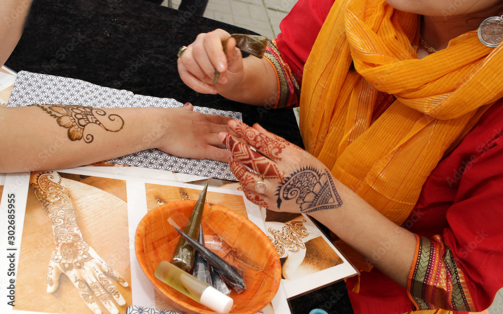 Artist applying henna tattoo on women hands. Mehndi is traditional ...