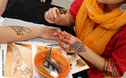 Artist applying henna tattoo on women hands. Mehndi is traditional Indian decorative art photo