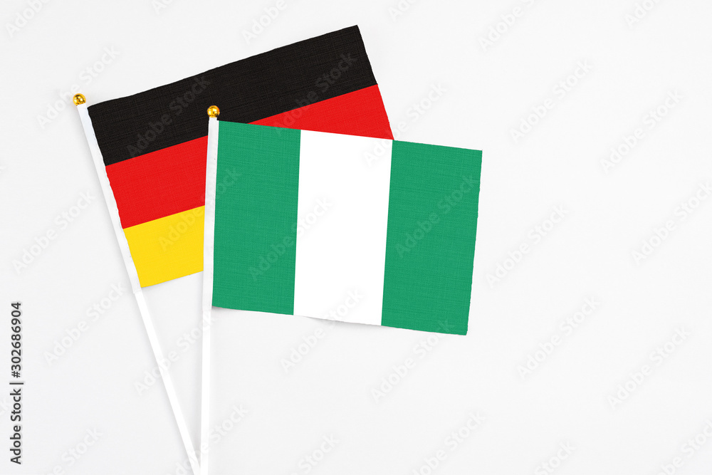 Nigeria and Germany stick flags on white background. High quality fabric, miniature national flag. Peaceful global concept.White floor for copy space. Nigeria and Germany stick flags on white background. High quality fabric, miniature national flag. Peaceful global concept.White floor for copy space.