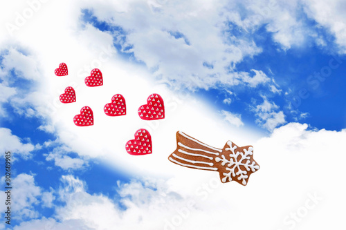 Creative composition with gingerbread comet and red hearts on blue sky background. Original Christmas or love concept 
