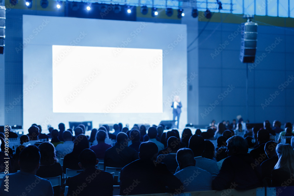 Speaker Giving a Talk at Business Meeting. Audience in the conference hall. blue tinted photo Focus on unrecognizable people - obrazy, fototapety, plakaty 