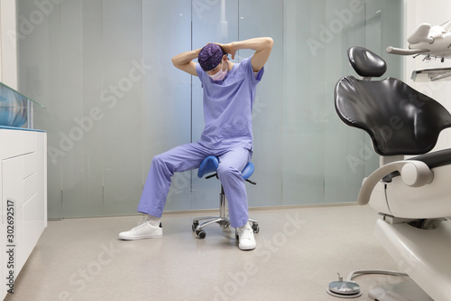 Dentist stretching neck.Caucasian man exercising on dental mobile saddle in his office.