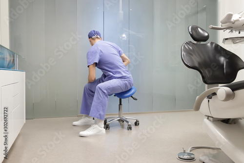 Dentist stretching body. Caucasian man exercising on dental mobile saddle in his office.