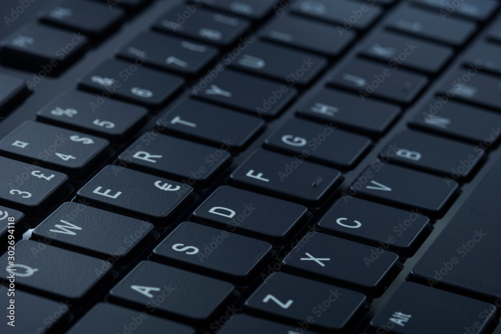 Close-up of a dark gray computer keyboard. Tilted angle, selective focus. Close-up of a dark gray computer keyboard. Tilted angle, selective focus.