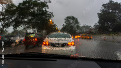 Waiting in the car during the rain. Dark cloud in the evening. Red led light from the back of the car.