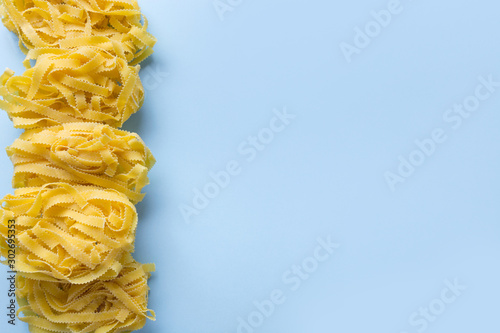 Tasty raw egg pasta shape reginella rolled up by portion on blue. Isolated. View from above. photo