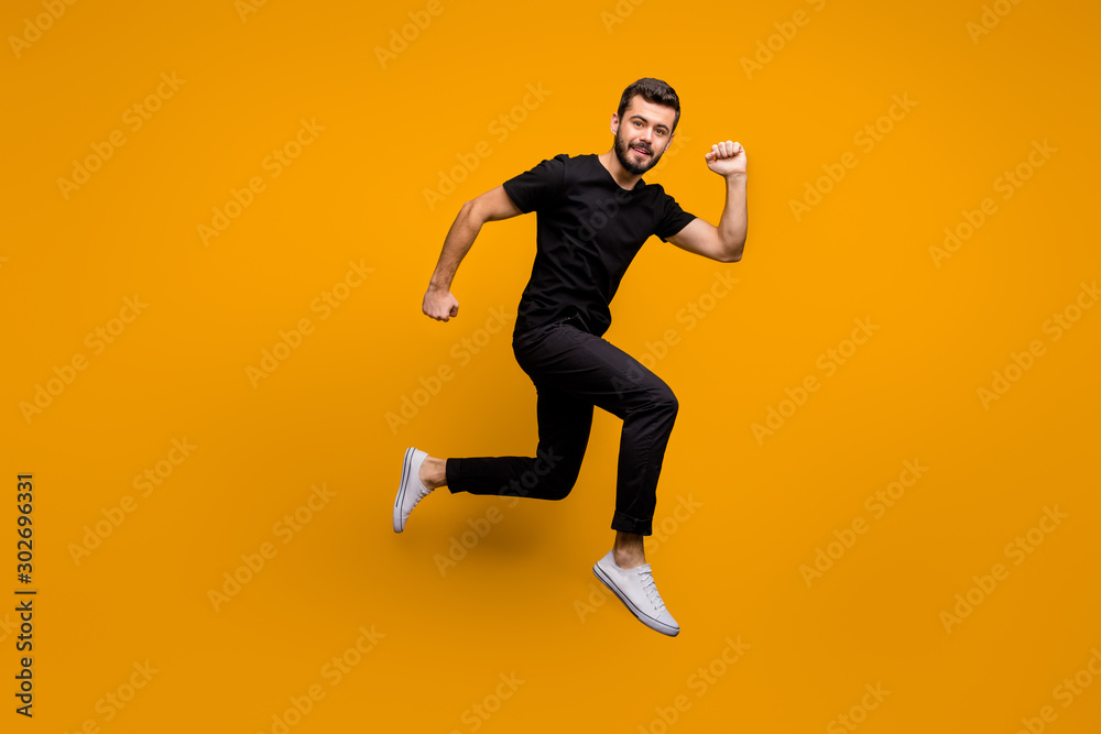 Full length profile photo of handsome millennial guy jumping high rush shopping mall black friday offers season wear black t-shirt pants isolated yellow color background