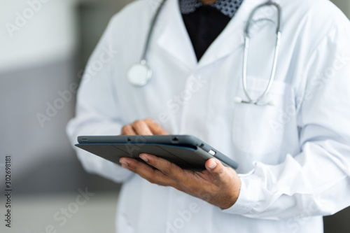 Close up of a doctor checking patient information via tablet.