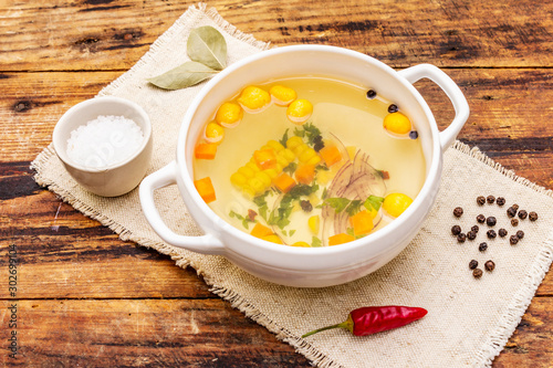 Transparent duck broth with dumplings and vegetables. Traditional bouillon, healthy food. Old wood background