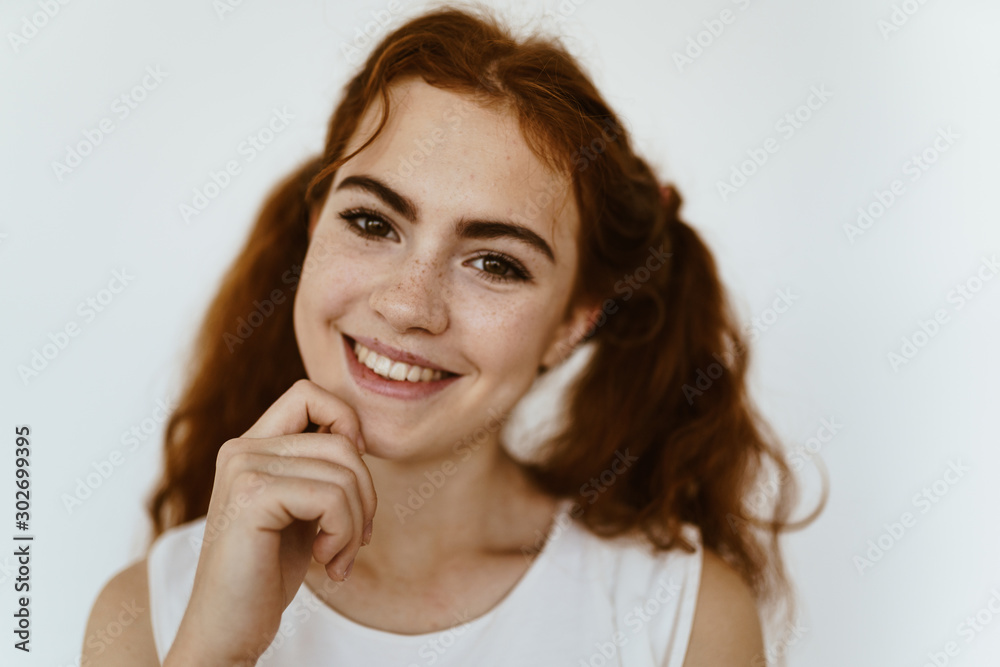 schoolgirl with a happy smile holds on to her chin. light background schoolgirl with a happy smile holds on to her chin. light background