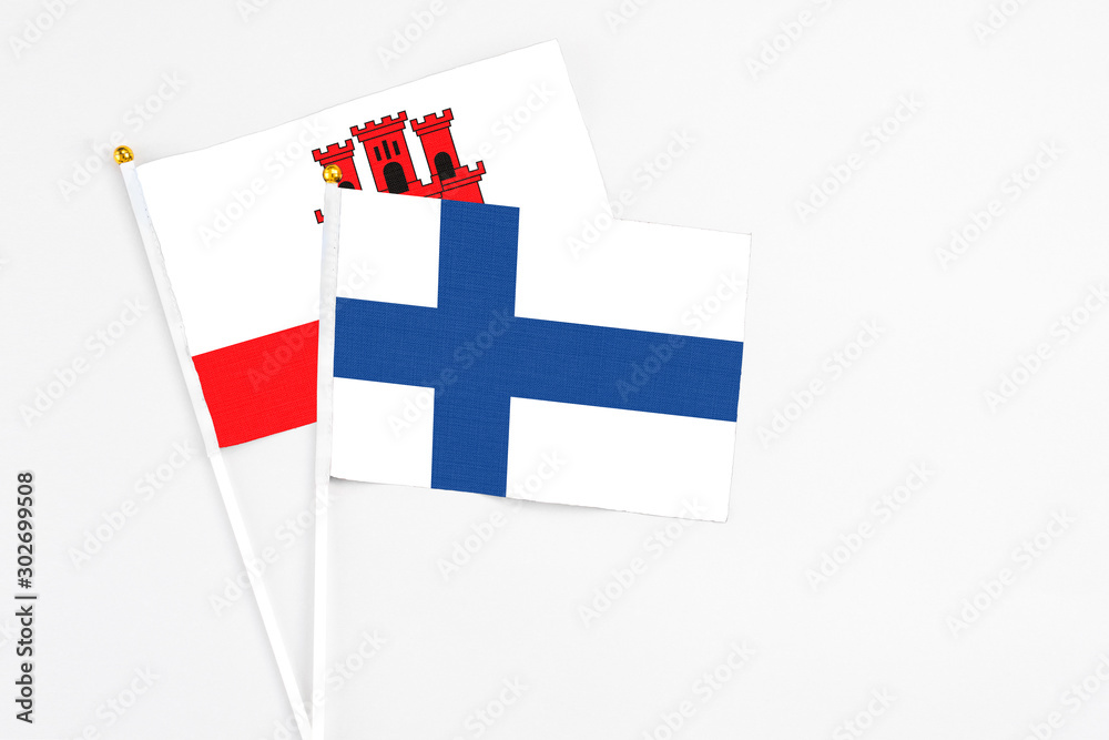 Finland and Gibraltar stick flags on white background. High quality fabric, miniature national flag. Peaceful global concept.White floor for copy space.