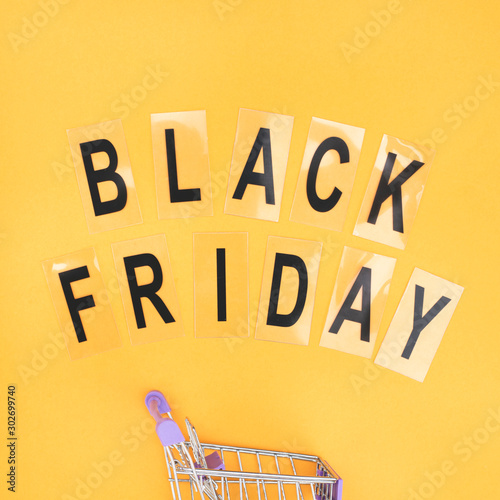 Wheelbarrow for shopping and the word black friday on orange background.