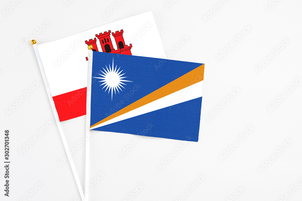 Marshall Islands and Gibraltar stick flags on white background. High quality fabric, miniature national flag. Peaceful global concept.White floor for copy space. Marshall Islands and Gibraltar stick flags on white background. High quality fabric, miniature national flag. Peaceful global concept.White floor for copy space.