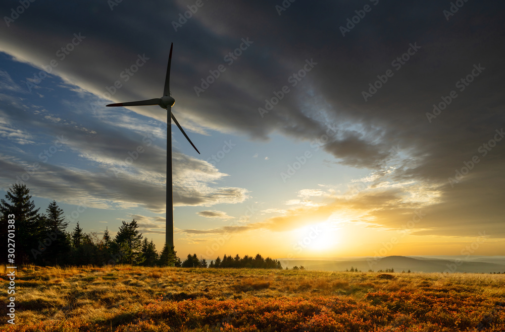 Obraz premium Wind power plant in mountain landscape at sunset with dramatic clouds