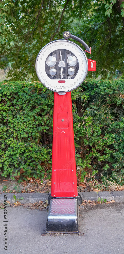 large red street scales for people on a green background plants. find out your weight on the street. weight measurement large red street scales for people on a green background plants. find out your weight on the street. weight measurement