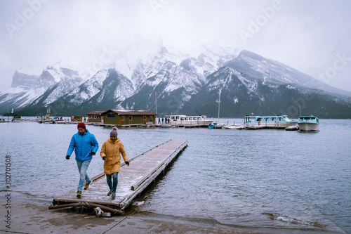 Lake Minnewanka Banff national park Canada, couple walking by the lake during snow storm in October in the Canadian Rockies Canada 
