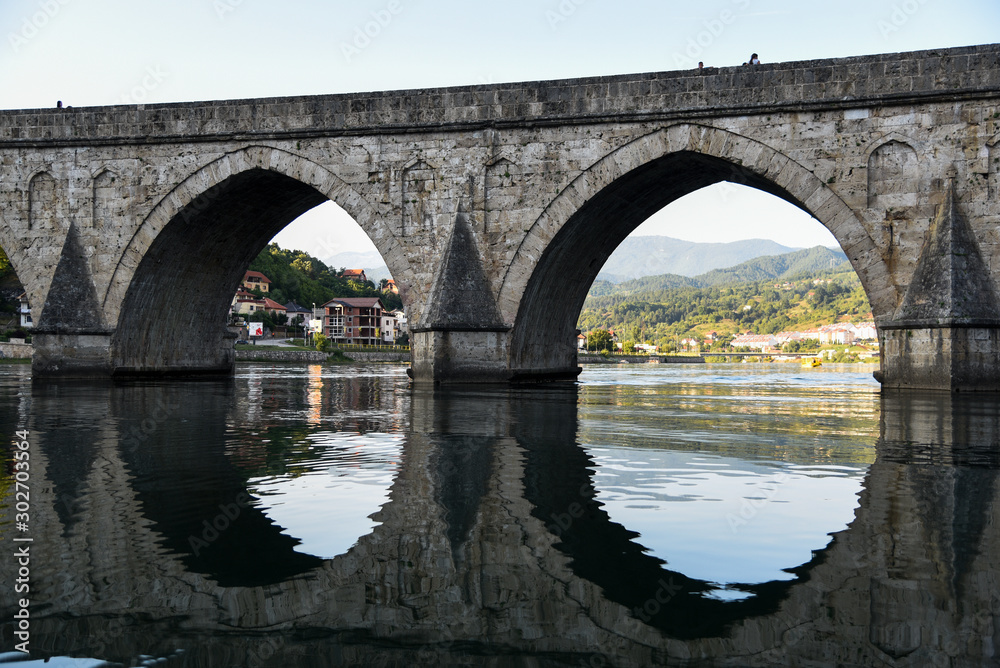 The Ottoman Mehmed Pasa Sokolovic Bridge over Drina river in Visegrad, Bosnian mountains, with fantastic  river reflection. Bosnia and Herzegovina.