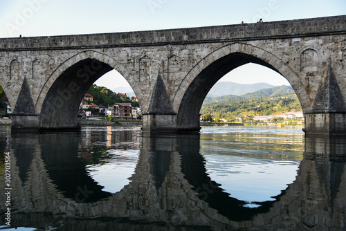 The Ottoman Mehmed Pasa Sokolovic Bridge over Drina river in Visegrad, Bosnian mountains, with fantastic river reflection. Bosnia and Herzegovina.