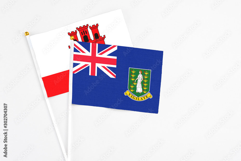 Fototapeta premium British Virgin Islands and Gibraltar stick flags on white background. High quality fabric, miniature national flag. Peaceful global concept.White floor for copy space.