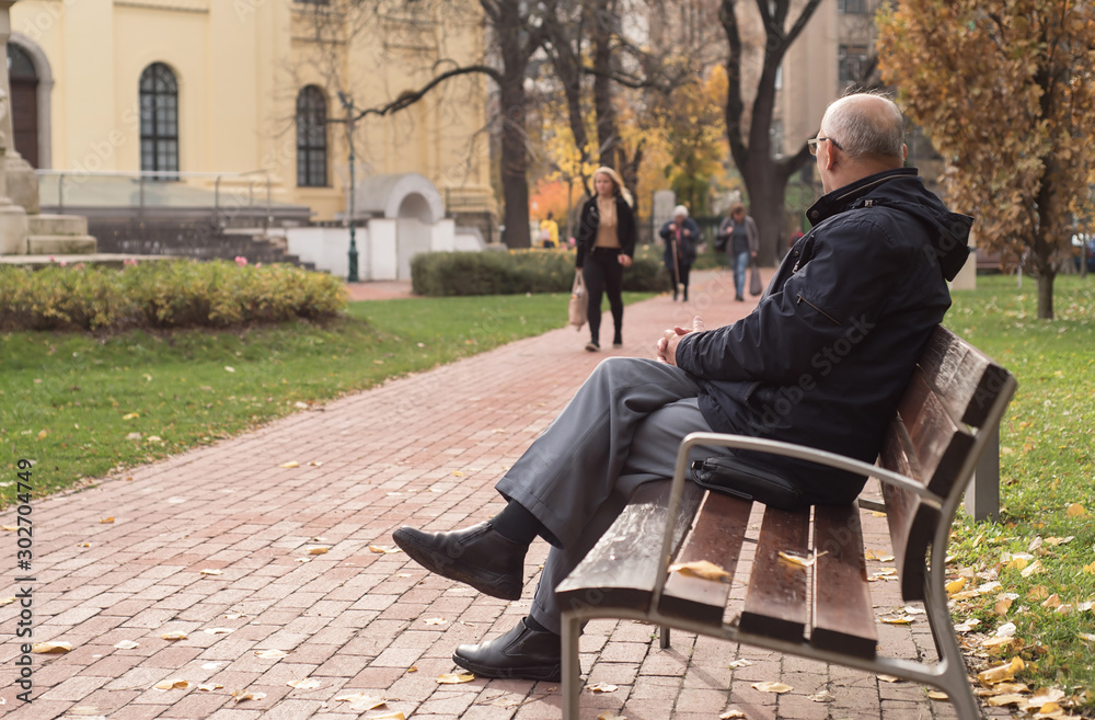 Old man sitting on a bench in the park Old man sitting on a bench in the park