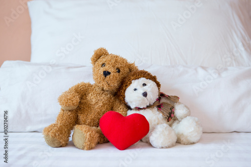 Two little teddy bear sitting on the bed with red heart, valentine concept background, relationship and love