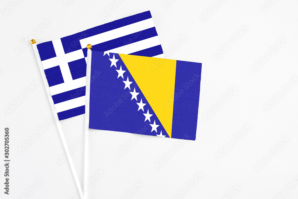 Bosnia Herzegovina and Greece stick flags on white background. High quality fabric, miniature national flag. Peaceful global concept.White floor for copy space.