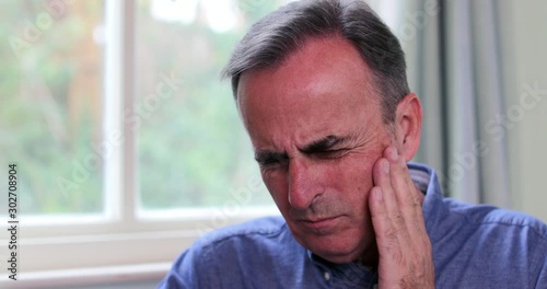 Mature Man Suffering With Toothache And Rubbing Painful Tooth